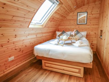 A bedroom with a bed with pillows and breakfast tray under a skylight window at Bluebell in St Harmon near Rhayader