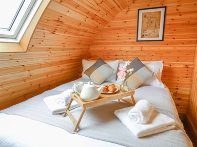 A bed with pillows towels and a breakfast tray in a wooden room at Bluebell in St Harmon near Rhayader