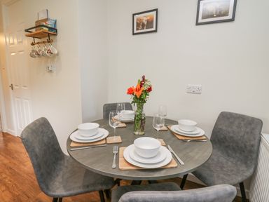 A dining room with a round table set for four and chairs at Ger Yr Afon Cottage in St Harmon near Rhayader