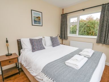 A bedroom with a double bed bedside tables lamps a window and wall art at Ger Yr Afon Cottage in St Harmon near Rhayader