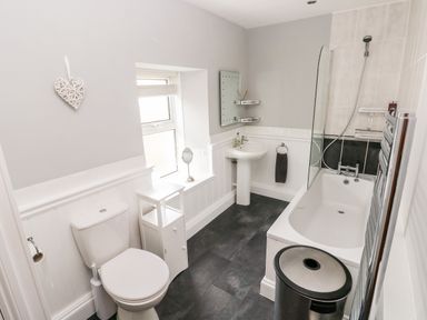 A bathroom with a toilet sink bathtub and small storage unit at The Old Bakery in Milton Tenby