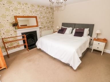 A bedroom with a double bed bedside tables a fireplace and a mirror at The Old Bakery in Milton Tenby