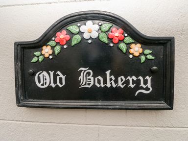 A black plaque with flowers and the words Old Bakery at The Old Bakery in Milton Tenby