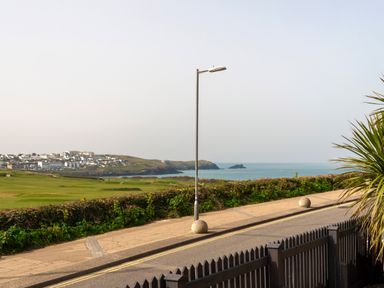 A coastal view with a grassy field a street lamp and ocean in the distance at Fistral Drift in Newquay