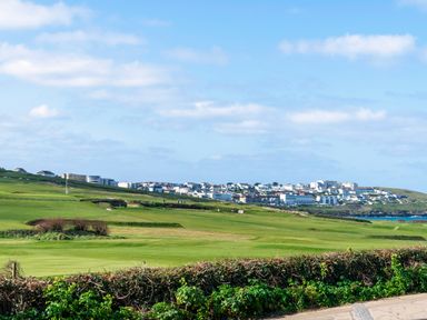 A golf course with green fields and houses in the background at Fistral Drift in Newquay