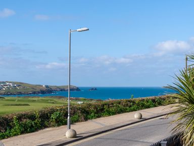 A coastal road with a street lamp and bushes overlooking the ocean at Fistral Drift in Newquay