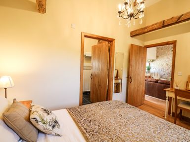 A bedroom with a bed pillows a lamp and doors leading to a bathroom and another room at Golwg Las in Pumsaint near Lampeter