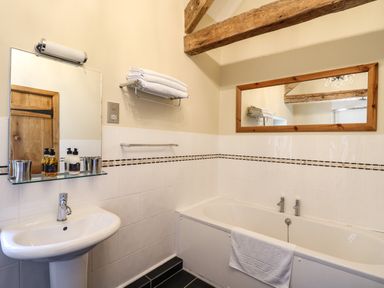 A bathroom with a bathtub a sink towels and two mirrors at Golwg Las Pumsaint near Lampeter