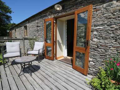 A stone exterior patio with two chairs and a small round table at Golwg Las in Pumsaint near Lampeter