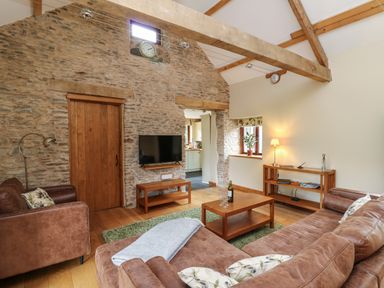 A living room with brown leather sofas wooden furniture and exposed stone walls at Nant Glas in Pumpsaint near Lampeter