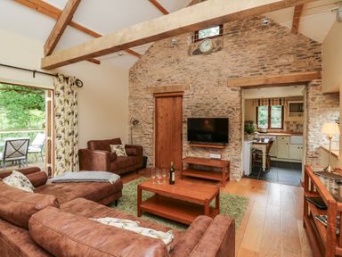 A living room with brown sofas wooden coffee table and a wall mounted television at Nant Glas Pumpsaint near Lampeter