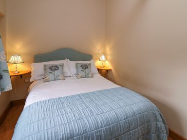 A bedroom with a double bed two bedside lamps and floral cushions at Nant Glas Pumpsaint near Lampeter
