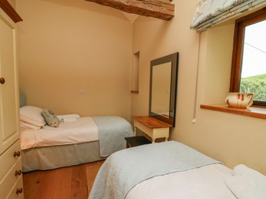 A bedroom with two single beds wooden floor a window and a dressing table at Nant Glas Pumpsaint near Lampeter