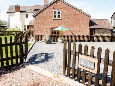 A fenced outdoor area with gravel and a brick house in the background at The Cider House in Leominster