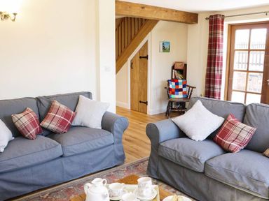 A living room with two gray sofas with cushions and a wooden coffee table with tea set at The Cider House in Leominster