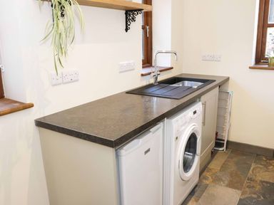 A utility room with a washing machine fridge sink and countertop at The Cider House in Leominster