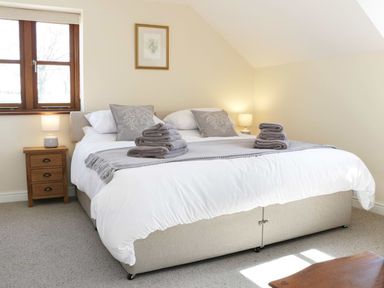 A bedroom with a double bed, bedside tables and lamps at The Cider House in Leominster