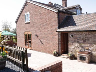 The exterior of a brick house with a wooden fence and potted plants at The Cider House in Leominster