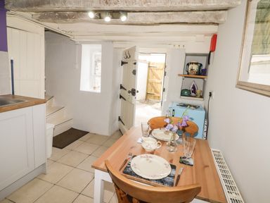 A small kitchen dining area with a wooden table set for two and a door leading outside at Kooky Cottage in Brecon