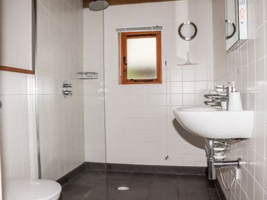 A bathroom with a sink toilet shower area and small window at Bybrook Lodge in Davidstow near Camelford