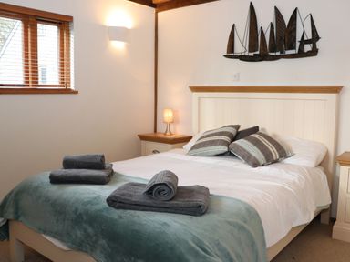 A bedroom with a double bed with folded towels on a teal throw and pillows on the bed at Bybrook Lodge in Davidstow near Camelford