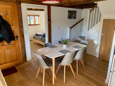 A dining area with a table and six chairs near a stairway and a bedroom at Bybrook Lodge in Davidstow near Camelford