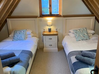 A bedroom with two single beds a nightstand and a lamp at Bybrook Lodge in Davidstow near Camelford