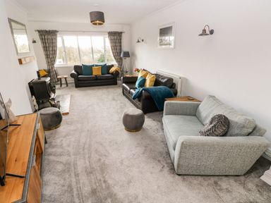 A living room with three sofas two side tables a floor lamp and a wood stove at The Dingle in Wisemans Bridge near Stepaside