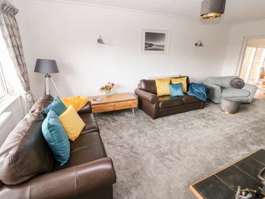 A living room with two brown leather sofas and one gray armchair with cushions a wooden coffee table and a floor lamp at The Dingle in Wisemans Bridge near Stepaside