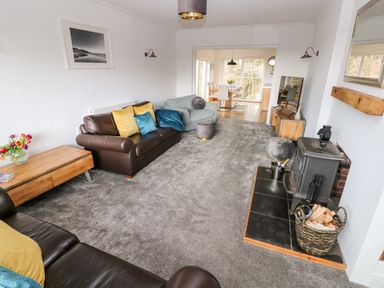 A living room with brown and grey sofas a wood burning stove and a wooden coffee table at The Dingle in Wisemans Bridge near Stepaside