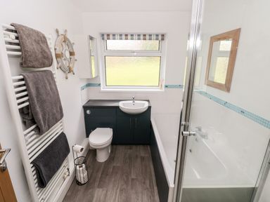A bathroom with a toilet sink bathtub towels and a window at The Dingle in Wisemans Bridge near Stepaside