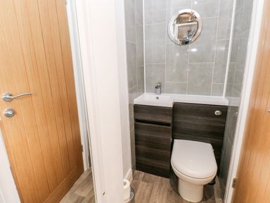 A small bathroom with a toilet sink and a round mirror at The Dingle in Wisemans Bridge near Stepaside