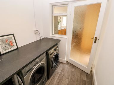 A laundry room with two washing machines a countertop and a door with etched glass at The Dingle in Wisemans Bridge near Stepaside