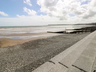 A pebble beach with concrete steps and wooden groynes along the shore at The Dingle in Wisemans Bridge near Stepaside
