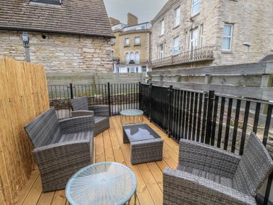 An outdoor patio with seating and a table at Still Waters in Swanage