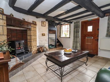 A living room with a fireplace wooden beams and a wooden door at Runnymede in Tewkesbury