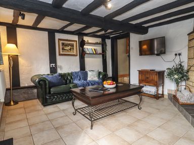 A living room with a green sofa a wooden coffee table and a wall-mounted TV at Runnymede in Tewkesbury