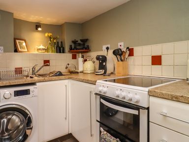A kitchen with a washing machine sink stove and utensils at Runnymede in Tewkesbury