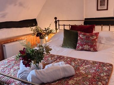 A bedroom with a bed and flowers on the bed at Runnymede in Tewkesbury