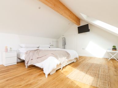 A bedroom with a bed side table and a wall mounted television at Apple Blossom Barn in Gulval near Penzance