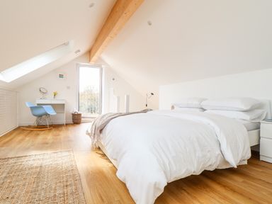 A bedroom with a bed a desk with a mirror and a blue rocking chair at Apple Blossom Barn in Gulval near Penzance