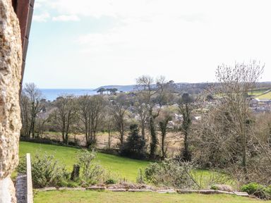 A landscape view with trees green grass and a distant sea at Apple Blossom Barn in Gulval near Penzance