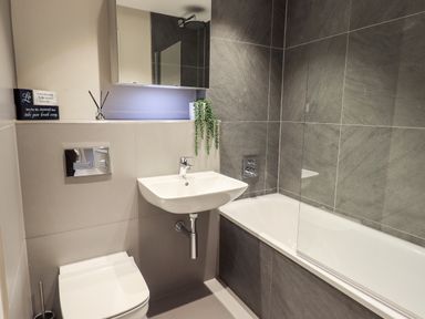 A bathroom with a toilet sink and bathtub with shower at Rivers Edge in Newby Bridge