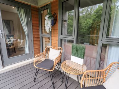 A balcony with two wicker chairs and a small round table with a potted plant at Rivers Edge in Newby Bridge
