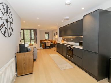 A kitchen with black cabinets and a dining table in the background at Rivers Edge in Newby Bridge