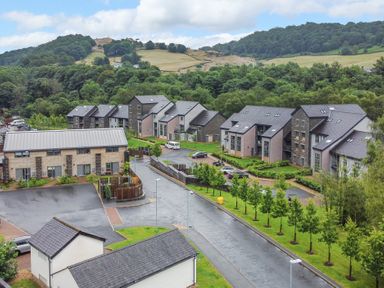 Residential buildings with parked cars along a street and trees in a rural area at Rivers Edge in Newby Bridge