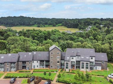 A residential building surrounded by trees and a parking area at Rivers Edge in Newby Bridge