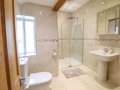 A bathroom with a toilet sink shower and a window at Craigside in Betws-Y-Coed