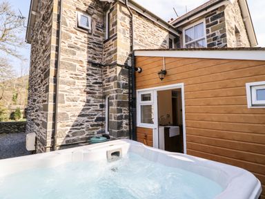 An outdoor hot tub next to a stone and wooden exterior of a house at Craigside in Betws Y Coed