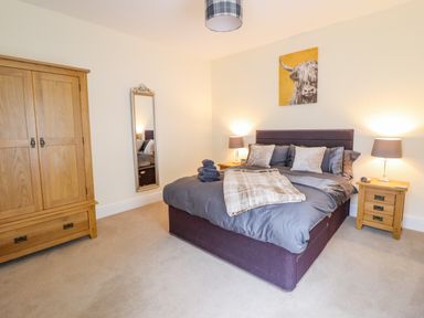 A bedroom with a double bed bedside tables lamps a wardrobe and a wall mirror at Craigside in Betws-Y-Coed